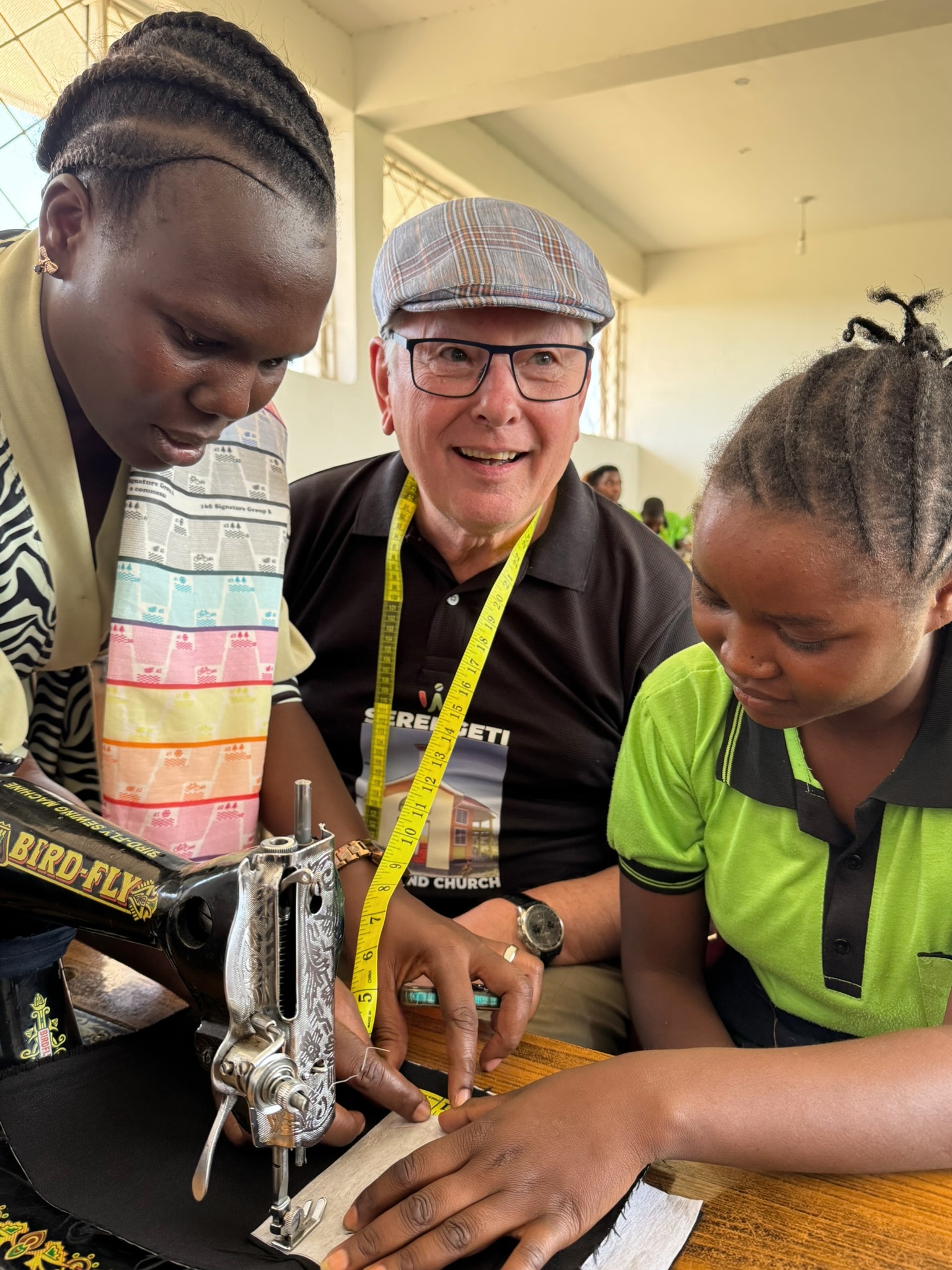 Lehrkraft zeigt Schülerinnen das Nähen an der Nähmaschine